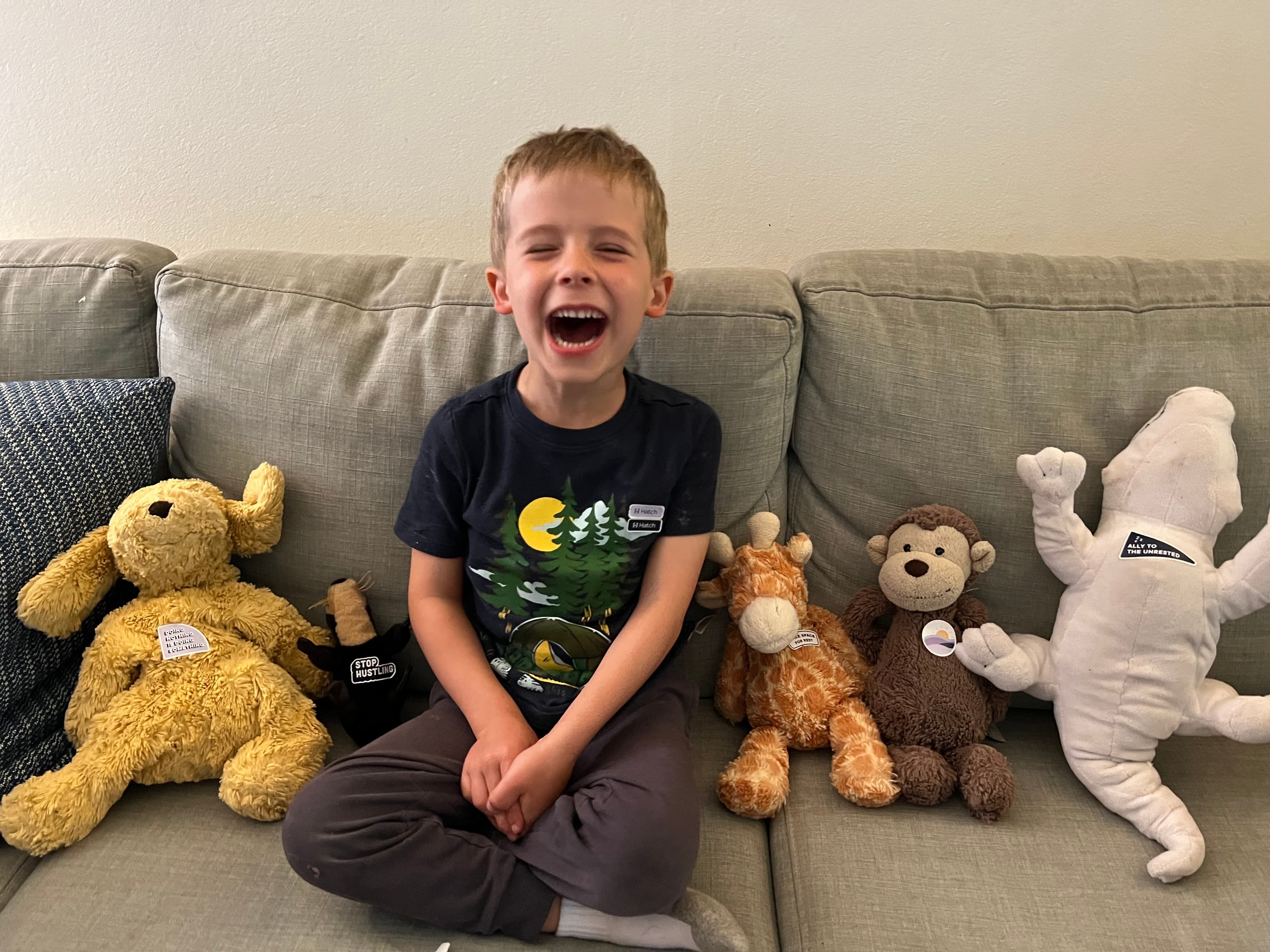 Boy playing on the couch with his stuffed animals